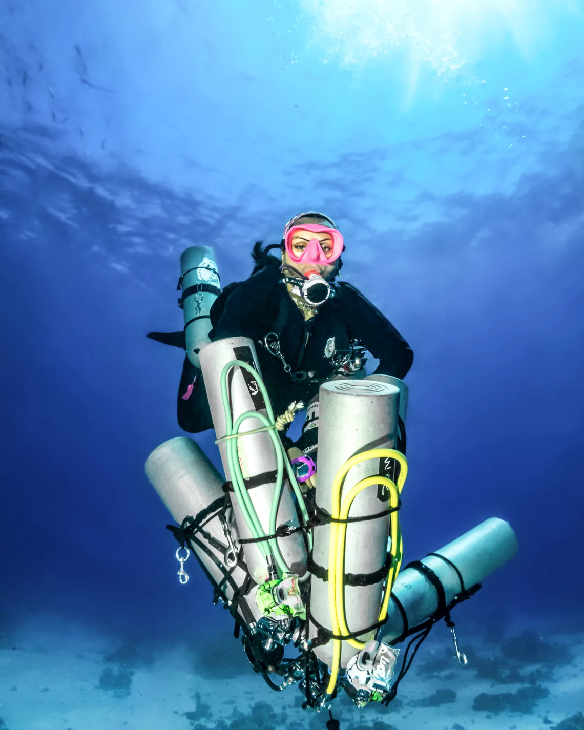 Technical diver carrying a stage cylinder over the reef